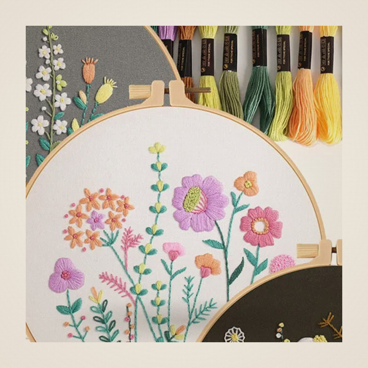 Détail du bouquet de fleurs roses et violettes brodé sur toile écrue